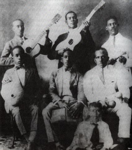 Historisches Schwarzweißfoto einer Gruppe von Musikern mit Gitarren in hellen Anzügen