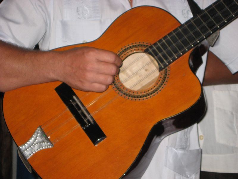 Nahaufnahme eines Tres, einer kubanischen Gitarre mit drei Saitenpaaren, in den Händen eines Musikers
